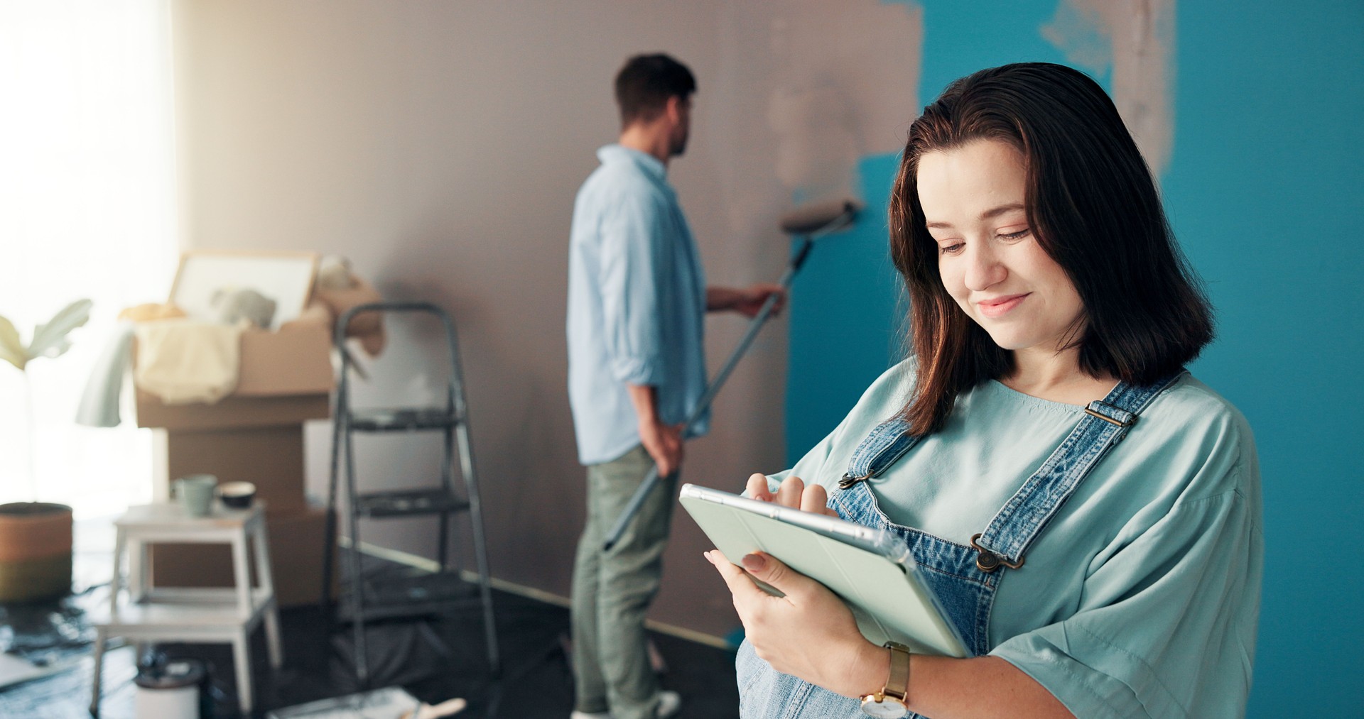 Couple, painting and woman in home on tablet for interior design, planning and renovation in family nursery. Pregnancy, marriage and people on digital tech for decoration, remodeling and DIY project